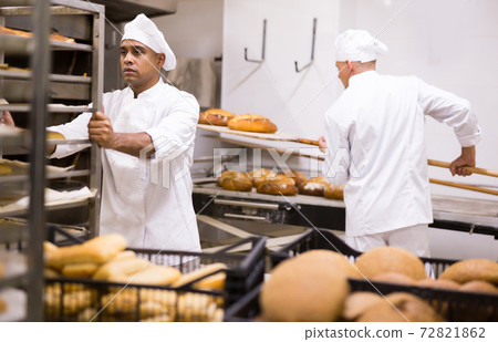 male baker rolling cart with bread in kitchen male baker rolling cart with bread in kitchen 72821862