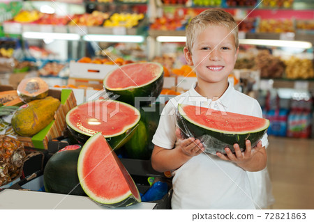 cute cheerful kid holding piece of watermelon at fruit section cute cheerful kid holding piece of watermelon at fruit section 72821863
