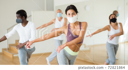 Group of multinational people in protective masks practicing dance techniques 72821864