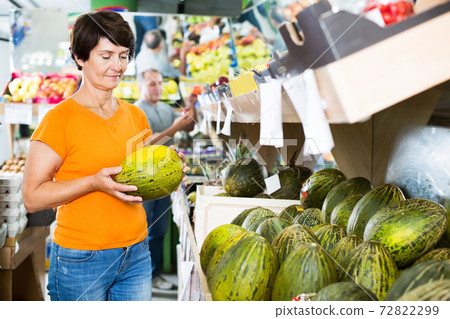 Female is choosing green melons 72822299