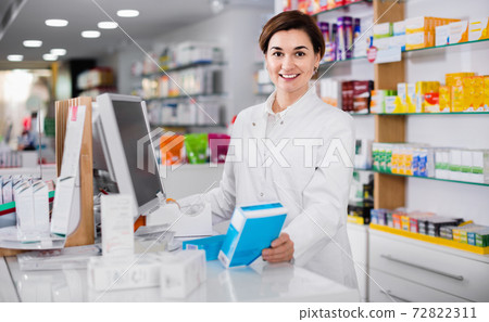 Female pharmacist offering help in choosing at counter in pharmacy Female pharmacist offering help in choosing at counter in pharmacy 72822311