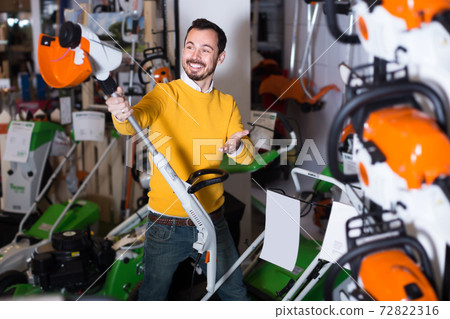 happy guy deciding on best manual lawnmower in garden equipment shop happy guy deciding on best manual lawnmower in garden equipment shop 72822316