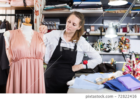 Serious woman professional standing near dress at mannequin Serious woman professional standing near dress at mannequin 72822416