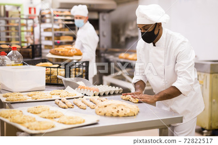 Male baker working with dough forming baguettes Male baker working with dough forming baguettes 72822517
