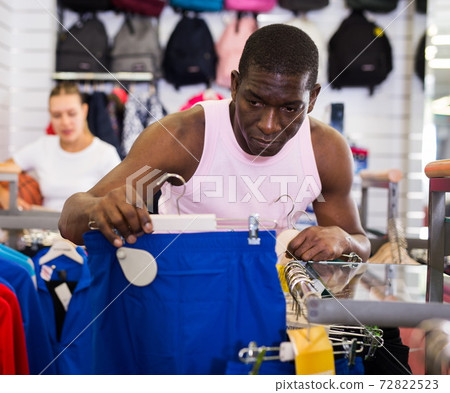 Man choosing sportswear in store Man choosing sportswear in store 72822523