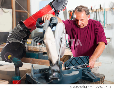 Carpenter cutting a wooden workpiece on an electical circular saw Carpenter cutting a wooden workpiece on an electical circular saw 72822525