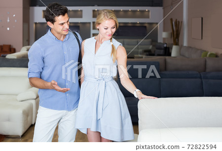 young man and woman are choosing sofa in store young man and woman are choosing sofa in store 72822594