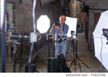 Portrait of satisfied photographer with his camera during photo shooting on town street 72822596
