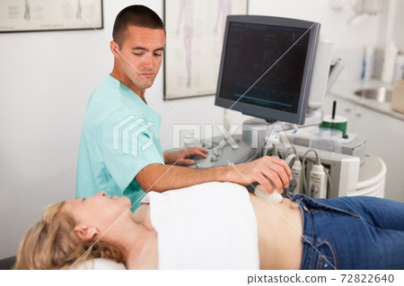Man examination woman at abdomen with ultrasonography device Man examination woman at abdomen with ultrasonography device 72822640