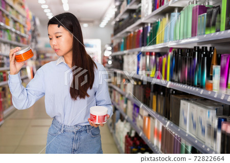 Portrait of young Asian woman choosing hair balm in supermarket Portrait of young Asian woman choosing hair balm in supermarket 72822664