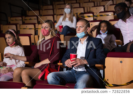 mother, father and their children sitting at film in auditorium during epidemic 72822856