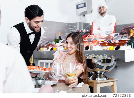 Smiling girl with man friend having dinner in fish restaurant 72822858