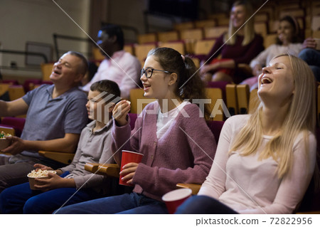 Cheerful parents with tween children watching comedy in cinema Cheerful parents with tween children watching comedy in cinema 72822956