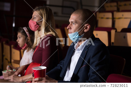 Man wearing medical mask watching movie in cinema 72823011