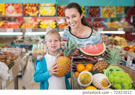 Portrait of happy woman and her little son with shopping cart full of fruits and vegetables Portrait of happy woman and her little son with shopping cart full of fruits and vegetables 72823012