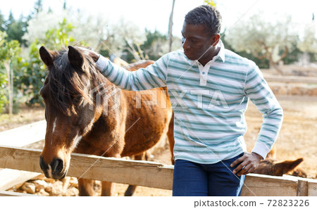 Farmworker carrying horse Farmworker carrying horse 72823226