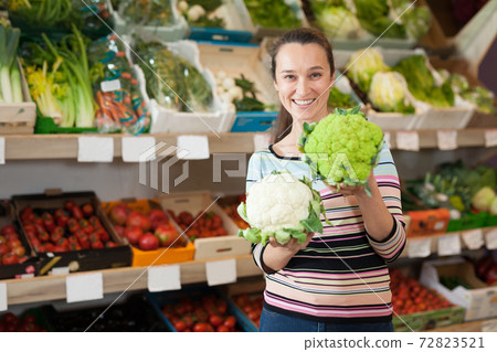 Woman holding broccoli and cauliflower 72823521
