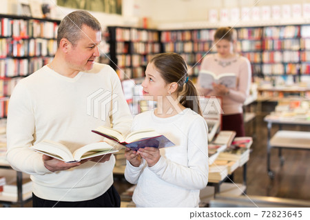 father and girl browsing textbooks father and girl browsing textbooks 72823645
