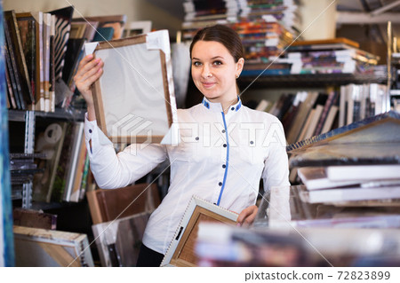 Girl is choosing modern picture in furniture store. Girl is choosing modern picture in furniture store. 72823899