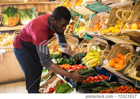 Seller arranging vegetables and fruits on counter Seller arranging vegetables and fruits on counter 72823917