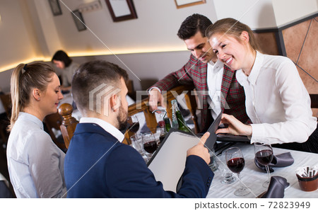 Young people sitting at table in restaurant, discussing menu Young people sitting at table in restaurant, discussing menu 72823949