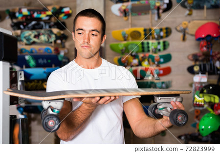 Portrait of man choosing skateboard in sporting goods store Portrait of man choosing skateboard in sporting goods store 72823999