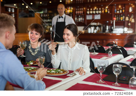 Women with male colleague at restaurant dinner 72824084
