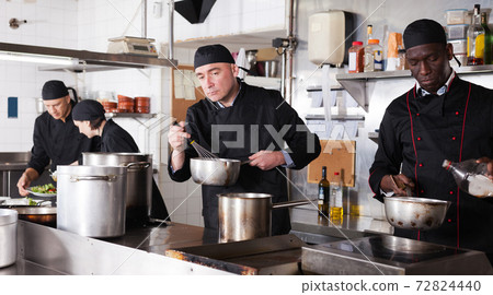 Chef with team preparing food in kitchen of restaurant 72824440