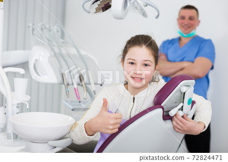 Girl in dental chair giving thumbs up 72824471