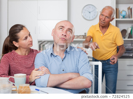 Wife calms husband after his quarrel with father Wife calms husband after his quarrel with father 72824525