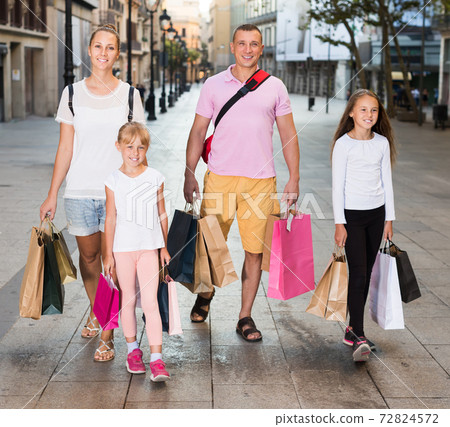 Man and woman with children walking and holding bags Man and woman with children walking and holding bags 72824572