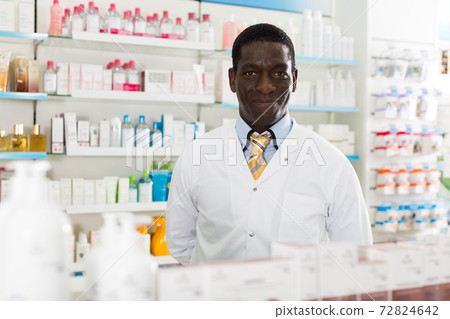 smiling male pharmacist in pharmacy 72824642