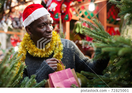 Smiling guy choosing fir tree Smiling guy choosing fir tree 72825001