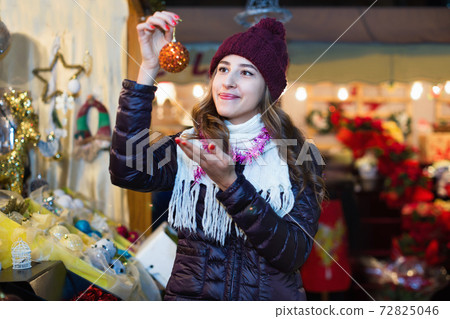 Beautiful young girl choosing Christmas decoration 72825046