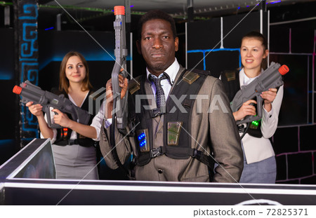 African male and jolly women holding laser guns African male and jolly women holding laser guns 72825371