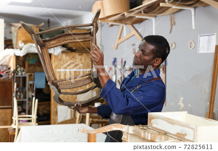 Craftsman restoring old chair in studio 72825611