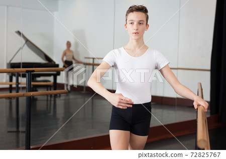 Positive teenager practicing at the ballet barre 72825767