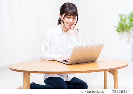 A lady who uses a laptop in the living room A lady who uses a laptop in the living room 72826354