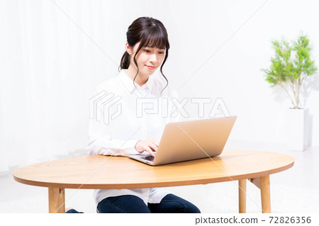 A lady who uses a laptop in the living room A lady who uses a laptop in the living room 72826356