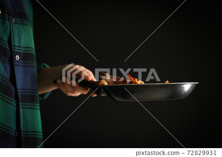Woman holding pan with fried bacon on black background Woman holding pan with fried bacon on black background 72829931
