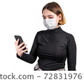 Young woman in medical protective mask with smartphone 72831976