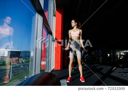 Athletic girl in sportswear performs exercises with barbell, dumbbells. Fitness, healthy lifestyle 72832000