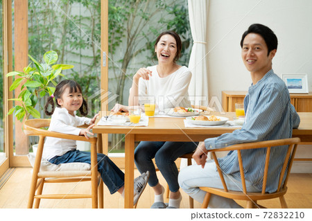 Portrait of a family of three, a girl eating breakfast, mom and dad 72832210