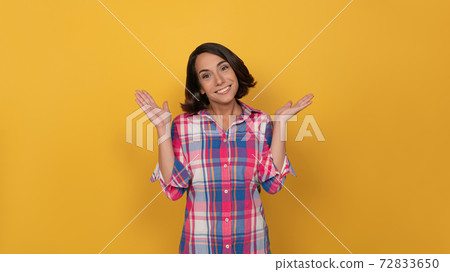 Oops i did it again young pretty woman posing on camera. Woman in a plaid shirt on yellow background. Human emotions, facial expression concept 72833650