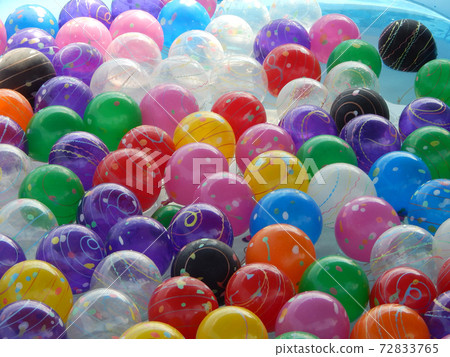 Small colorful plastic balls left floating in a small pond for children to play. Small colorful plastic balls left floating in a small pond for children to play. 72833765