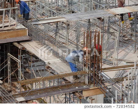 KUALA LUMPUR, MALAYSIA -JUNE 20, 2017: Construction workers fabricating steel reinforcement bar at the construction site. The reinforcement bar was tied together using tiny wire. KUALA LUMPUR, MALAYSIA -JUNE 20, 2017: Construction workers fabricating steel reinforcement bar at the construction site. The reinforcement bar was tied together using tiny wire. 72834582