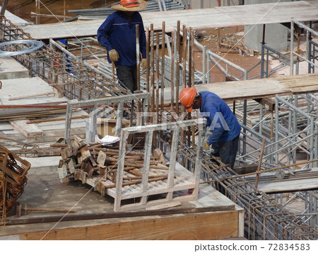 KUALA LUMPUR, MALAYSIA -JUNE 20, 2017: Construction workers fabricating steel reinforcement bar at the construction site. The reinforcement bar was tied together using tiny wire. 72834583