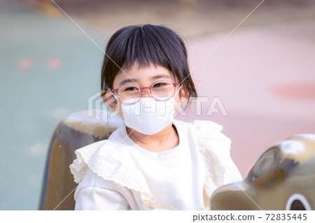 Girl wearing a mask and playing in the park 72835445