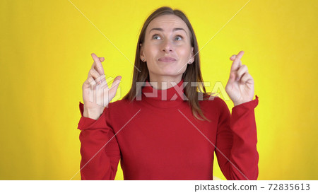 Young woman look camera bit lips hands folded in prayer beg about something good keep fingers crossed making wish isolated on yellow background in studio.  72835613