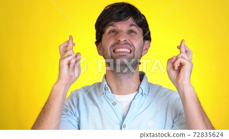 Young man look camera bit lips hands folded in prayer beg about something good keep fingers crossed making wish isolated on yellow background in studio.  72835624